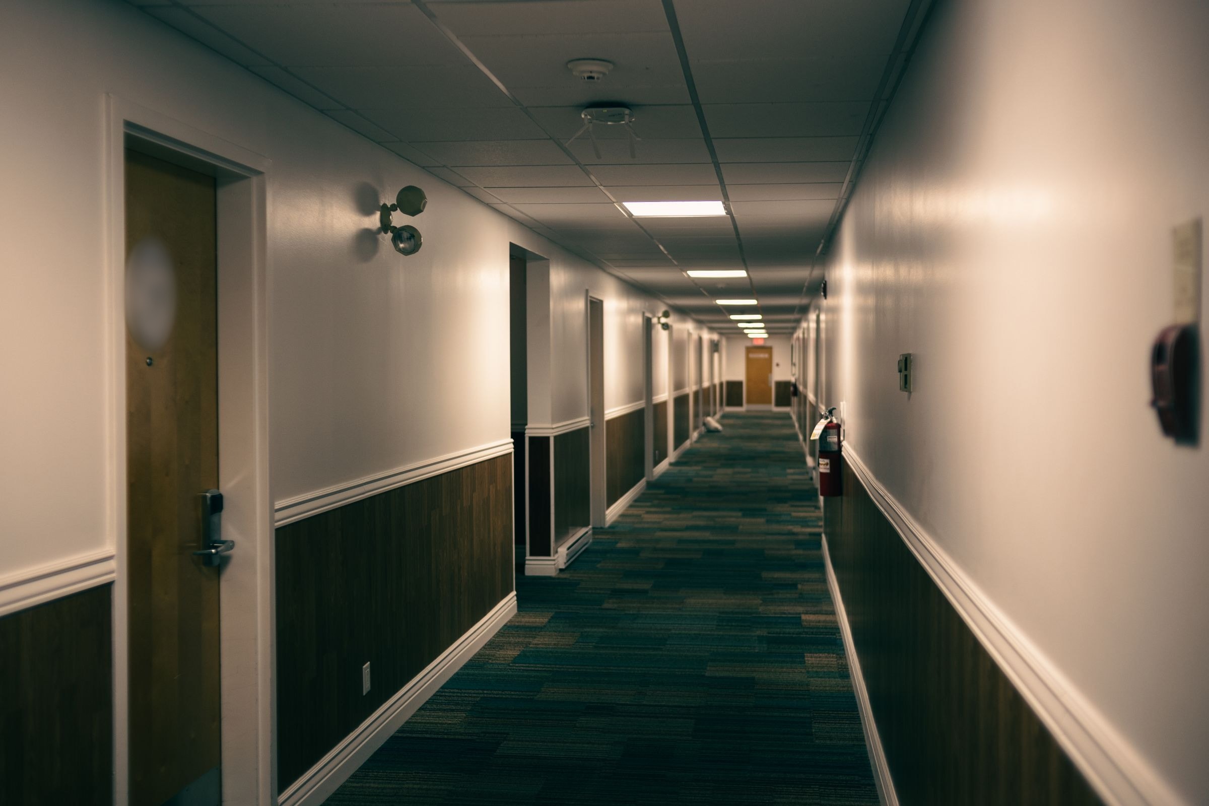 A commercial corridor lined with wood doors and lever hardware
