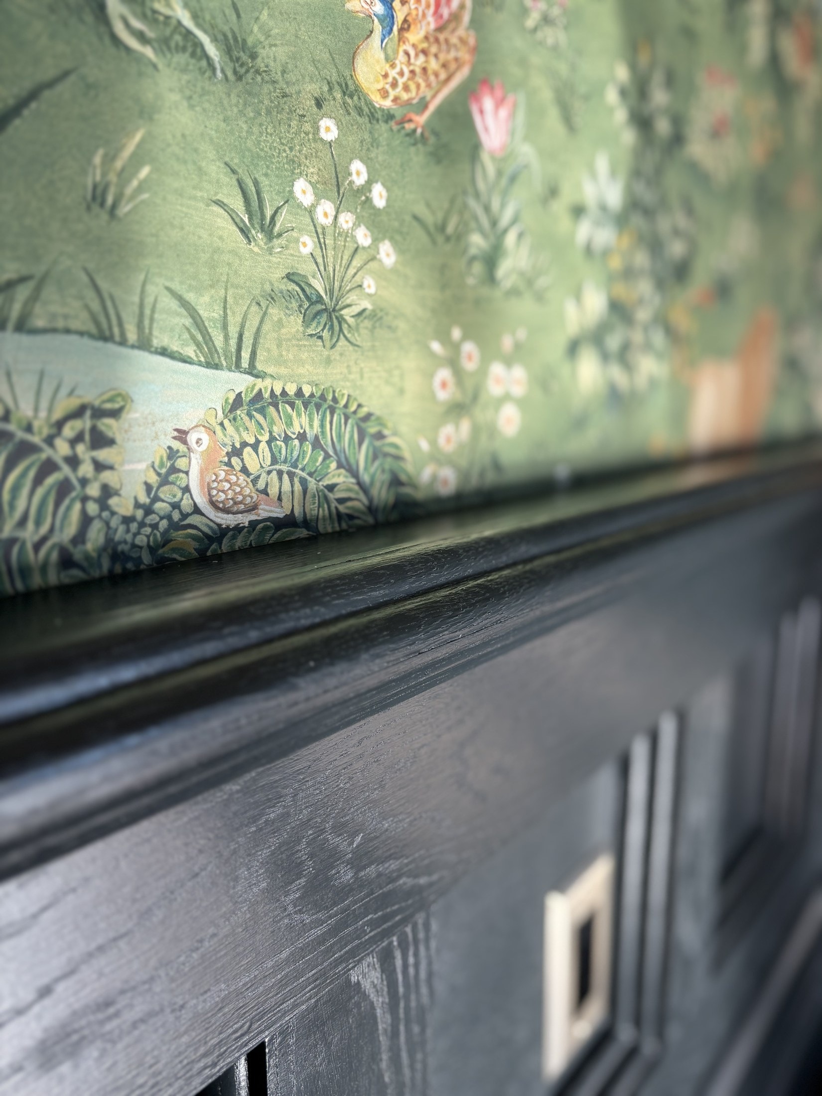Close-up of black trim and casing meeting patterned wallpaper