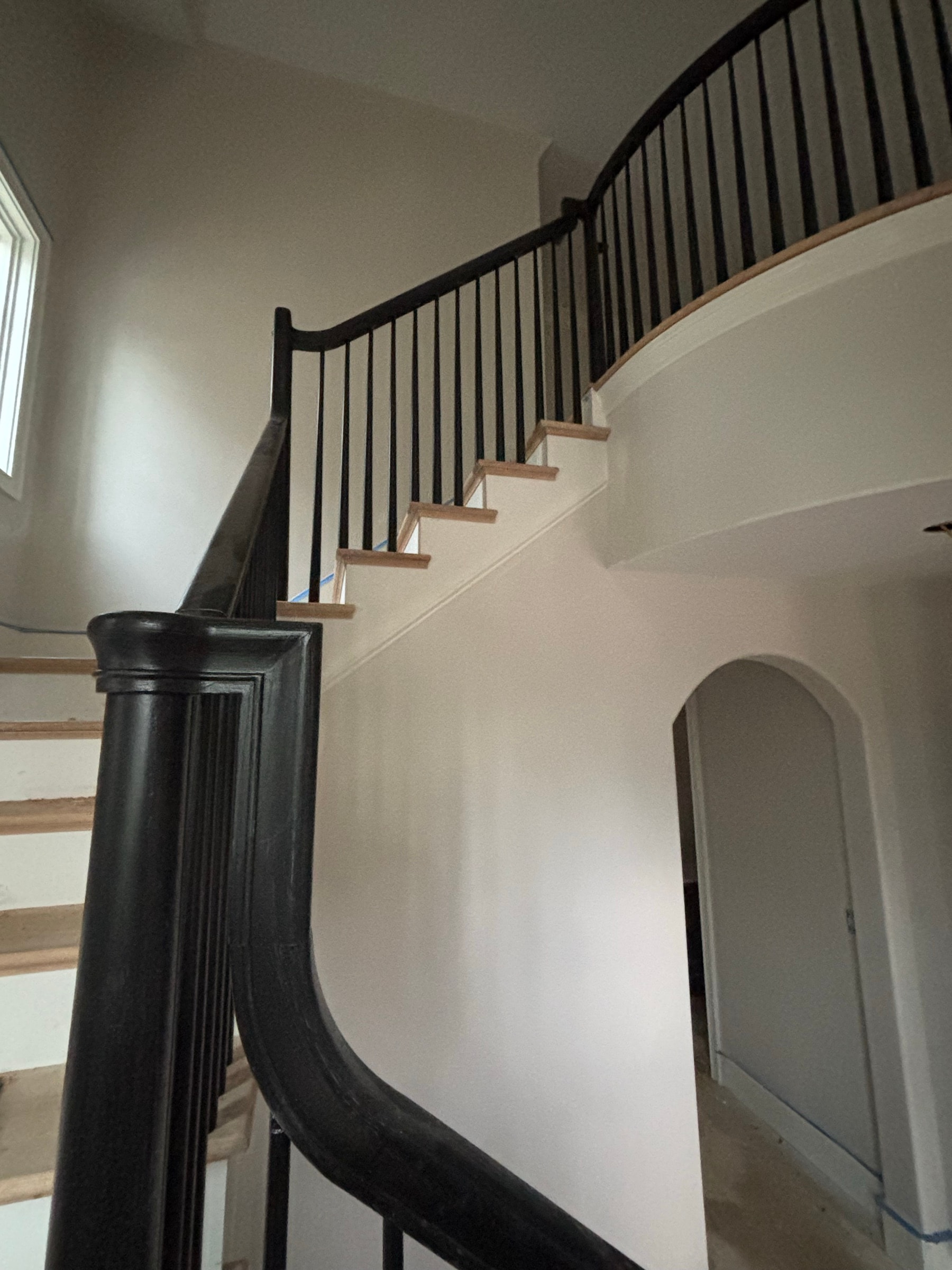 Curved staircase rising through a bright two-story foyer