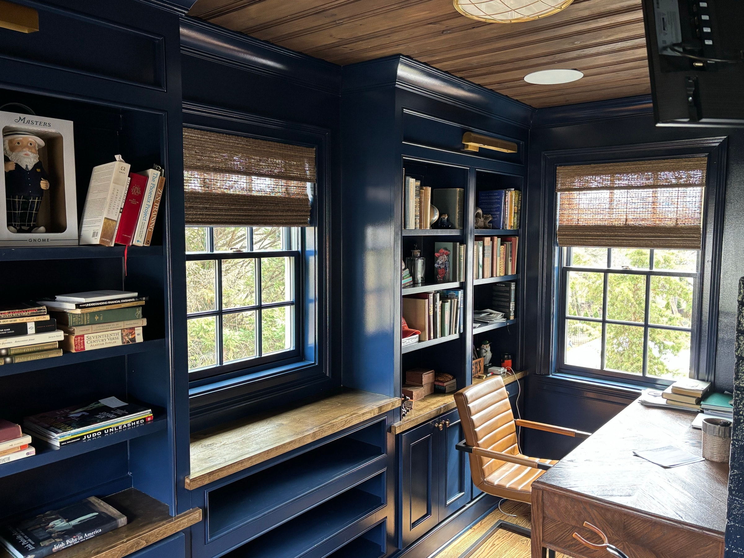 Navy-blue study built-ins with shelving and cabinetry around windows