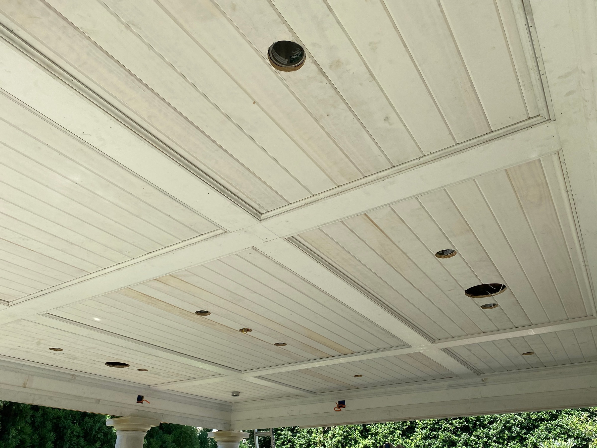 White tongue-and-groove plank ceiling with beams and recessed lighting