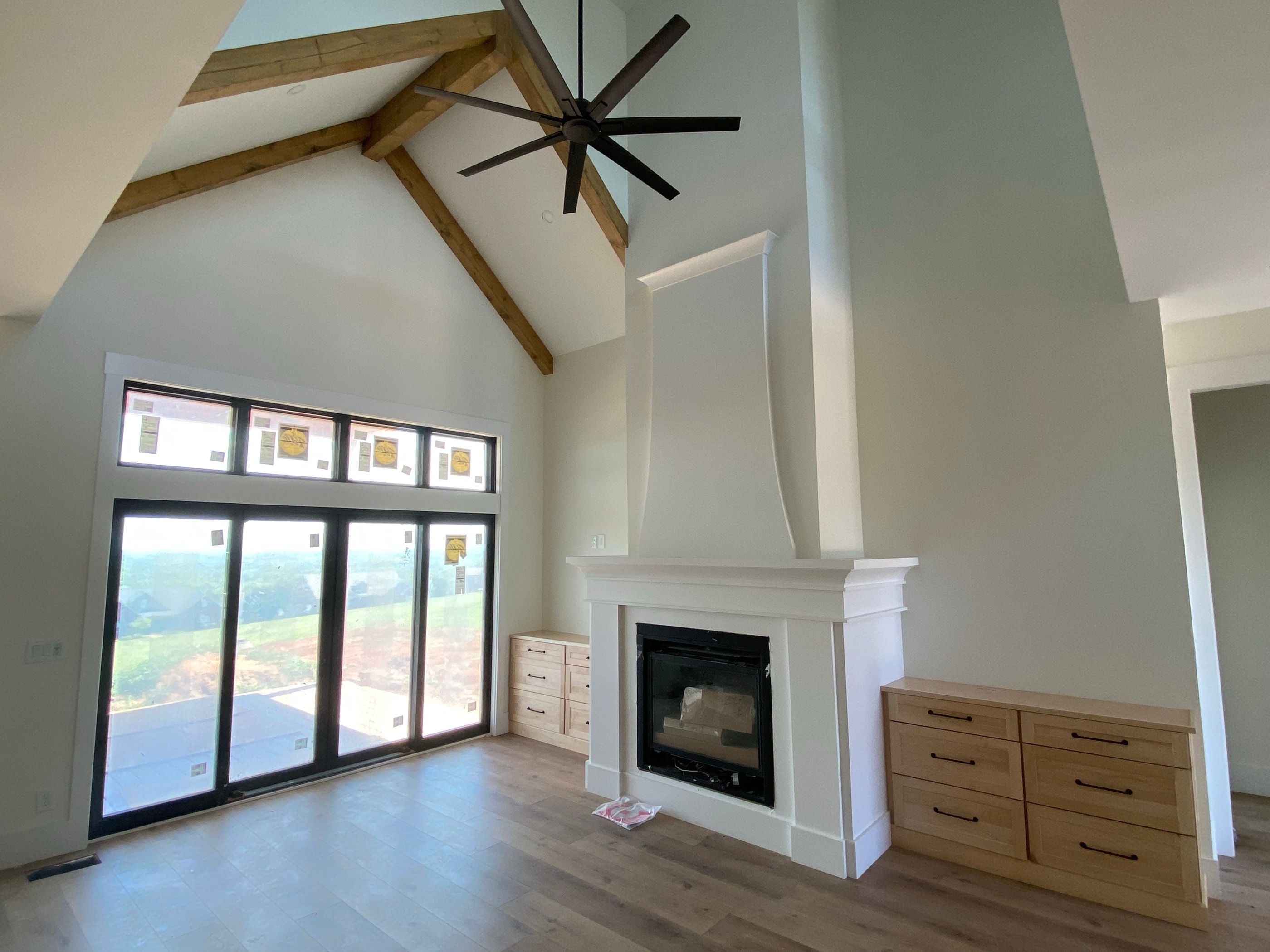 Vaulted great room with stained beams, a stone fireplace, and flanking built-ins